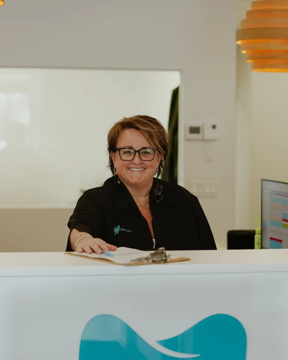 Accueil de la clinique Go Dentiste : une adjointe administrative souriante derrière le comptoir