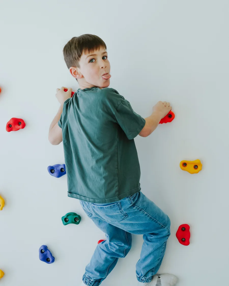 Un enfant grimpe sur le mur d'escalade de la salle de jeux