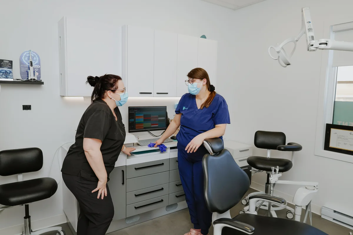 Assistante et hygiéniste qui préparent une salle de soins